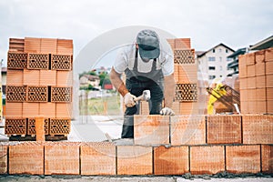 Details of industrial bricklayer installing bricks on construction site