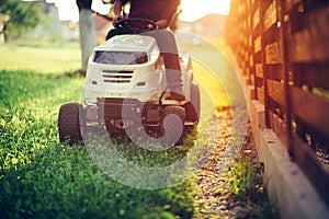 Details of landscaping and gardening. Worker riding industrial lawnmower