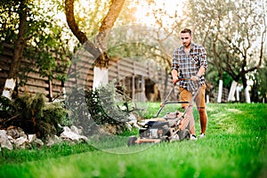 details of landscaping and gardening. Worker using industrial manual lawnmower