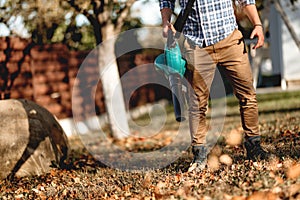 Details of man using garden blower