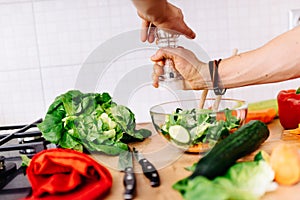 Details of mens hands adding salt and pepper to salad. perfect cook preparing salad for healthy life