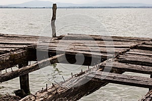 Details of an old, broken pier on a lake, with nails and worn and missing wood boards