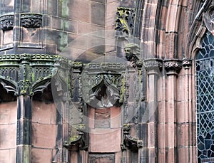 Details of ornately carved medieval stonework with niches and faces on the facade of chester cathedral