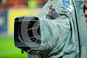 Details of a professional television camera, with rain cover, live broadcasting a soccer game