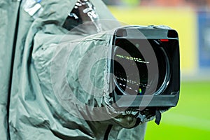 Details of a professional television camera, with rain cover, live broadcasting a soccer game