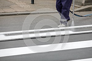 Details with a road worker painting a crosswalk on a city street