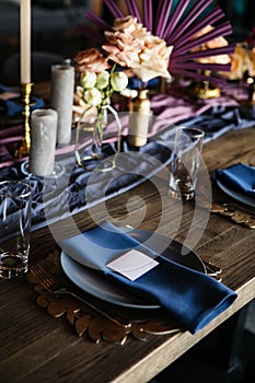 Details of serving on a banquet. Luxurious decor on the wedding table. candles, flowers, gold and blue elements.