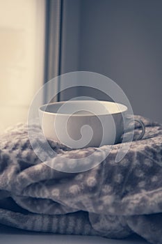 Details of still life in the home interior. Sweater, cup, wool, cozy, book, candle. Moody. Cosy autumn winter concept.