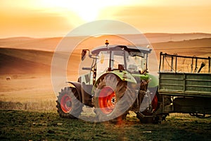 Details of tractor, farmer working in the fields with tractor on a sunset background. Agriculture industry details