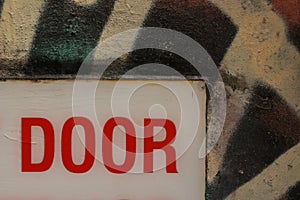 details of a warning sign on a back entry door in a side alley covered in graffiti, detail showing only the word \