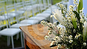 details of a wedding altar with an outdoor wooden table with white chairs in front of a green field and flowers