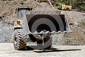 Details of wheel loader with empty scoop and bucket working on construction site