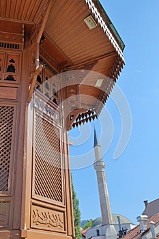 Details of the wooden fountain Sebilj, located in the main square of  Bascarsija district, with a minaret in the background