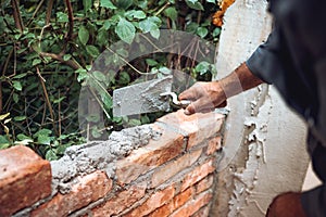 Details of worker, bricklayer placing and adjusting bricks with mortar. Professional construction worker building exterior walls