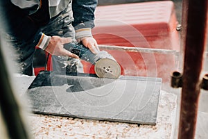 Details of worker cutting stone marble with angle grinder at construction site