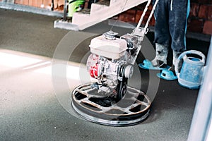 Details of worker finishing concrete screed with power trowel machine on construction site