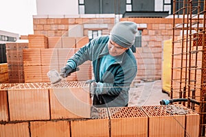 Details of worker hands laying bricks, putty knife and rubber hammer and brick mortar