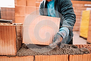 Details of worker hands laying bricks, putty knife, spatula and brick mortar