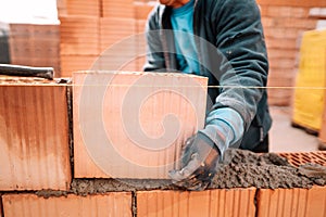 Details of worker hands laying bricks, putty knife, spatula and brick mortar