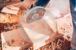 Details of worker using angle grinder for cutting bricks on construction site