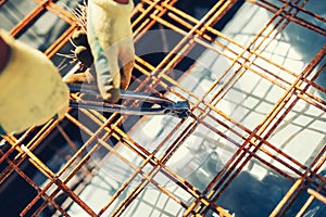 details with worker using wire rod and pliers for securing reinforcement steel bars on house building