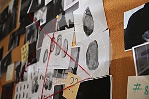 Detective board with crime scene photos, stickers, clues and red thread, closeup