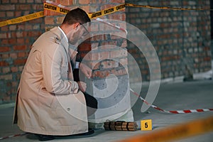 Detective in coat is on the crime scene with explosive bomb