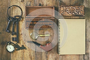 Detective concept. Private Detective tools: magnifier glass, old keys, smoking pipe, notebook. top view. vintage filtered image