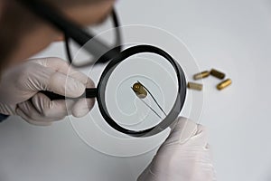 Detective exploring bullet shell with magnifying glass, closeup