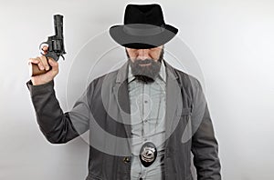 Detective with hat covering the eyes and police badge holding gun with the arm raised.