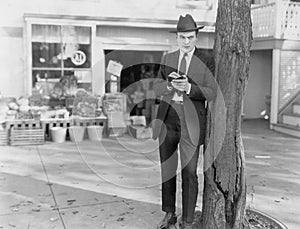 Detective leaning against tree taking notes