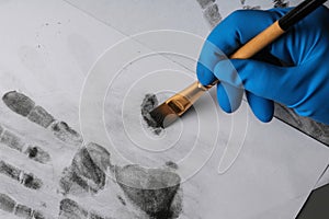 Detective taking fingerprints with brush from paper, closeup