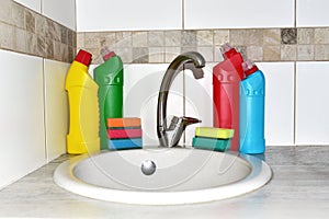 Detergent bottles and sponge near the kitchen sink at home. Detergents and laundry concept. Kitchen sponges and household