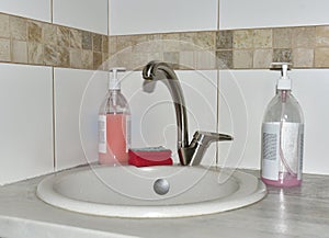 Detergent bottles and sponge near the kitchen sink at home. Detergents and laundry concept. Kitchen sponges and household