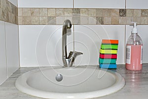 Detergent bottles and sponge near the kitchen sink at home. Detergents and laundry concept. Kitchen sponges and household