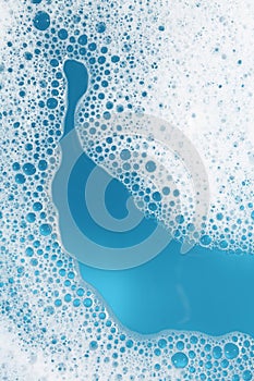 Detergent foam with bubbles on light blue background, top view