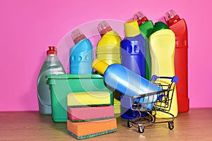 Detergent laundry bottles and sponge for washing on pink background. Household for cleaning and washing. Concentrated and anti-