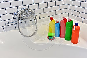 Detergent and sponge in bathroom on background of white tiles. Detergents bottles and kitchen sponges. Household chemicals