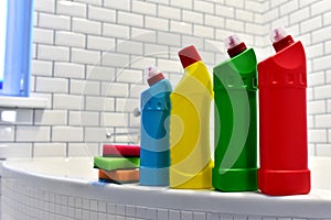 Detergent and sponge in bathroom on background of white tiles. Detergents bottles and kitchen sponges. Household chemicals