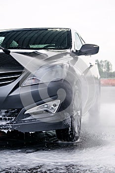 Detergent is washed off the front of a car with water