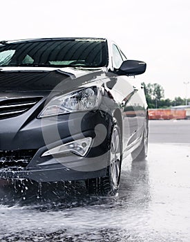 Detergent is washed off the front of a car with water