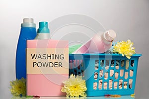 Detergents, powder, bleach, soiled laundry in basket on light gray .