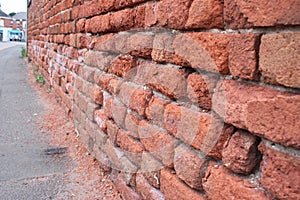 Deteriorating brick wall due to surface water from road traffic UK