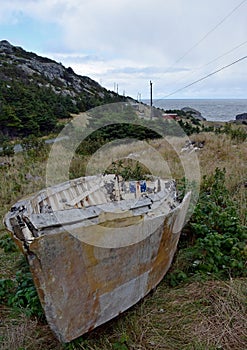 Deteriorating dory fishing boat on land in a meadow