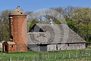 Deteriorating hip roofed barn and brick silo