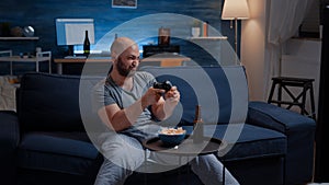 Determinated excited man sitting on sofa playing video games