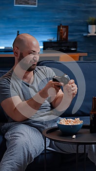 Determinated excited man sitting on sofa playing video games