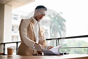 A determined Asian businessman searching for a document, concentrate on a document on a table