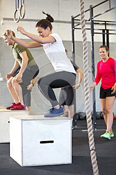 Determined Athletes Doing Box Jumping In Health Club