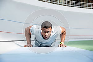 Determined athletic man doing push-ups at the stadium